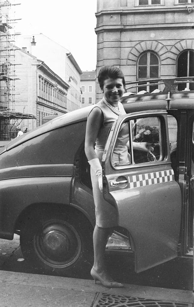 Esküvőre érkező vagy távozó hölgy taxiba száll. 1961. Baross utca, szemben a Rigó utca, a sarkon az épülő szövetkezeti ház. - Fotó: Fortepan / Somos Éva