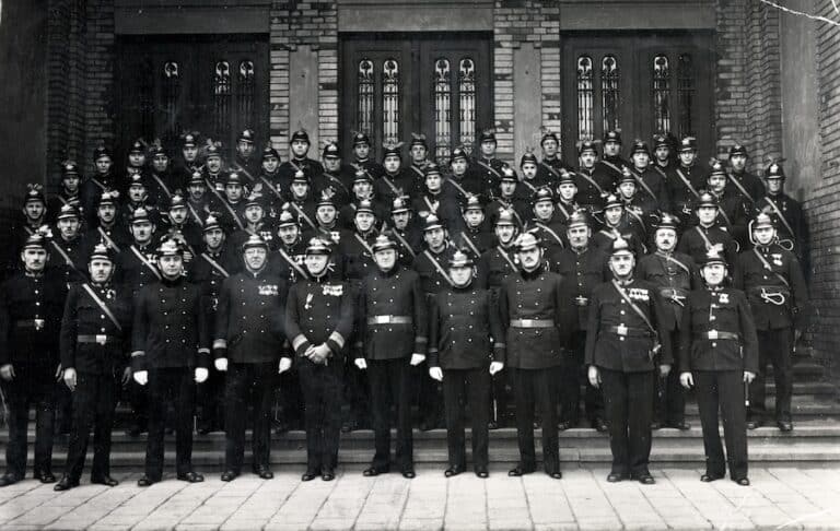 Címlapi fotó: tűzoltók 1931-ben a a MÁVAG kolónia Kultúrházának, ún. teremépületének főbejárata (Golgota út 3.) előtt Forrás: Fortepan / Hózer Benjámin